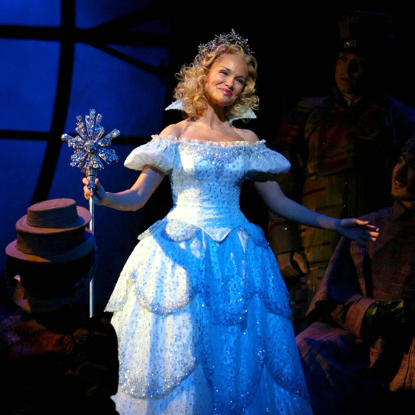 Kristen Chenoweth as Glinda in a performance of Wicked, wearing a blue ball gown and holding a wand.