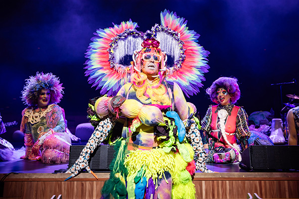 Machine Dazzle in a colorful costume performing in Bark of Millions