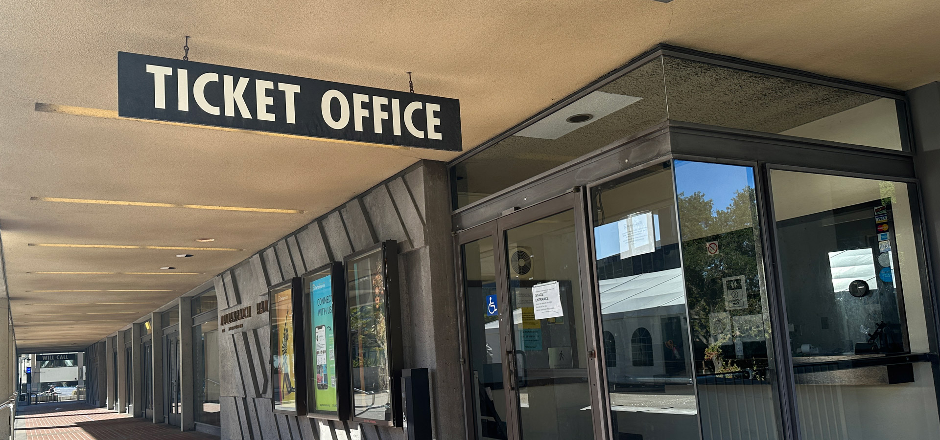 Sign that reads "Ticket Office" hanging from the ceiling outside of a box office stations.