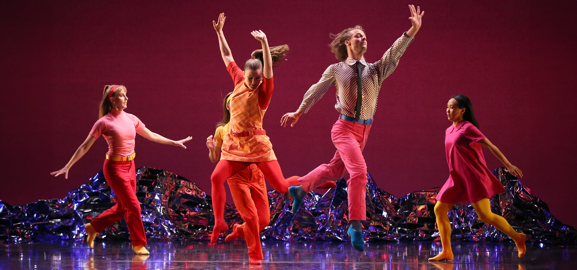 The Mark Morris Dance Group members perform Pepperland in bright red and orange costumes.