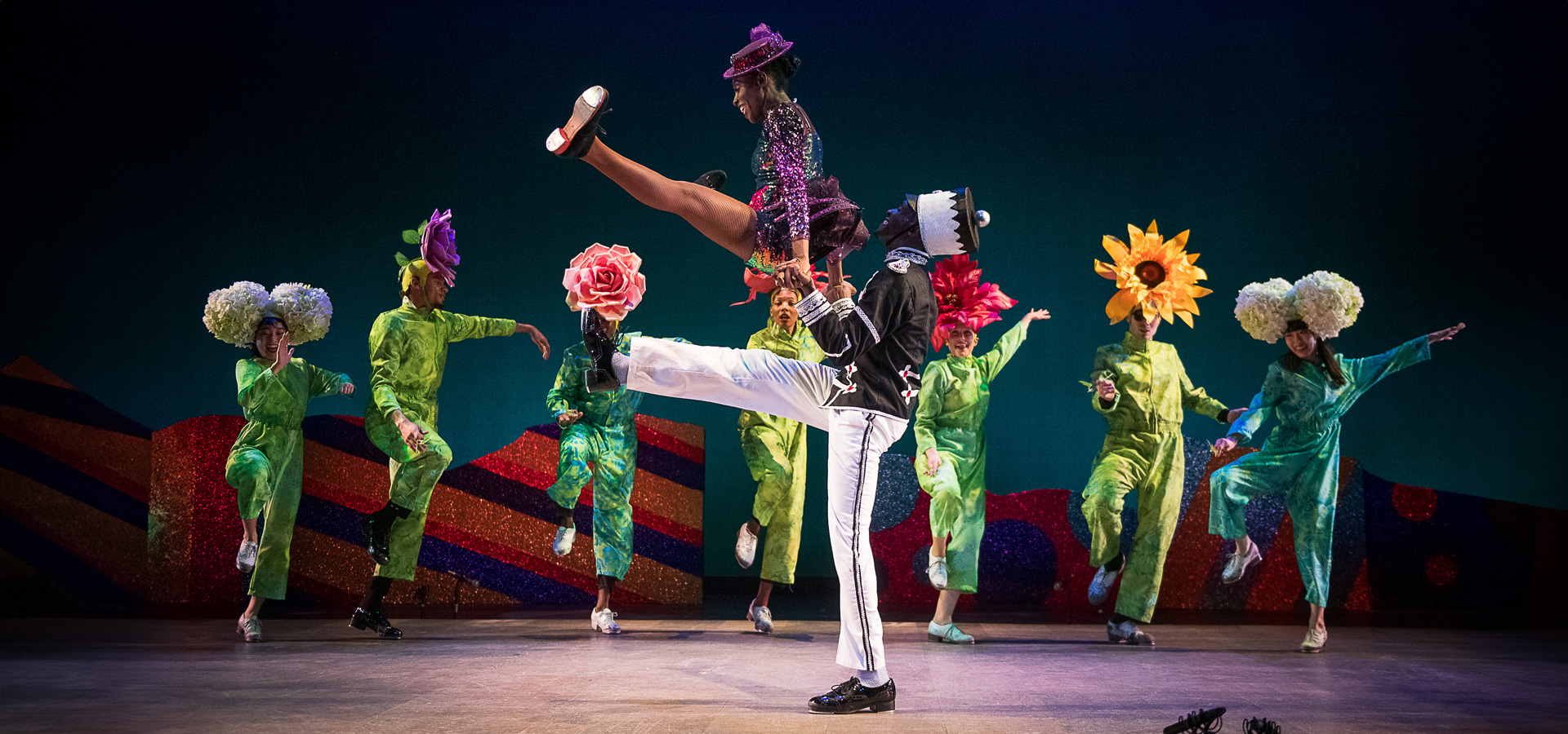 Dancers in colorful flower costumes perform on stage in the Dorrance Dance group's interpretation of Tchaikovsky's Nutcracker Suite.