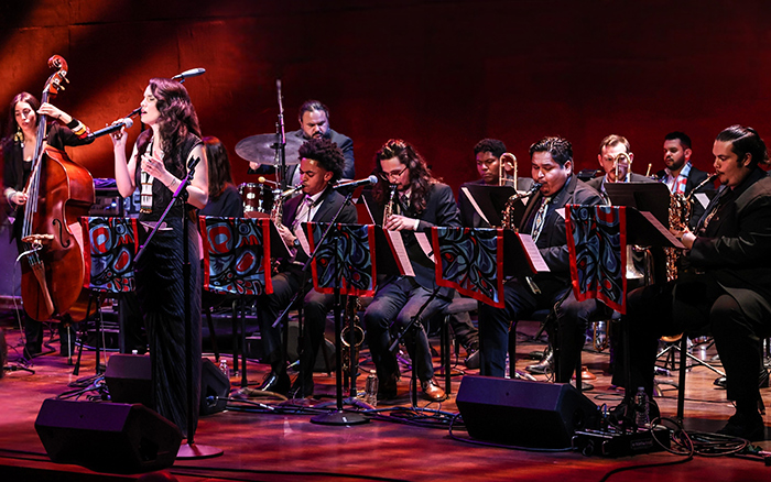 The Julia Keefe Indigenous Big Band performs on a dimly lit stage in front of an audience.