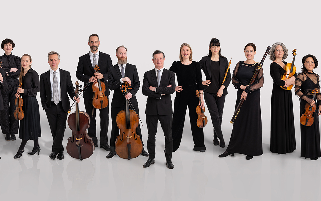 Ensemble photo of The English Concert, a group of white male and female musicians with their instruments all in a long, single line against a white background.