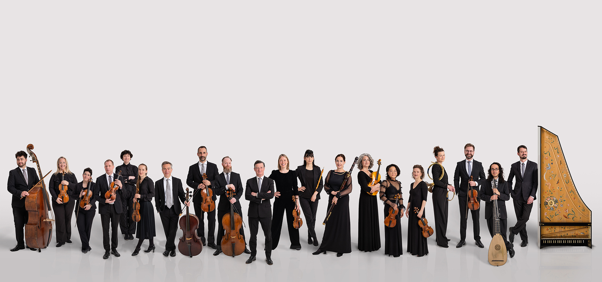 Ensemble photo of The English Concert, a group of white male and female musicians with their instruments all in a long, single line against a white background.