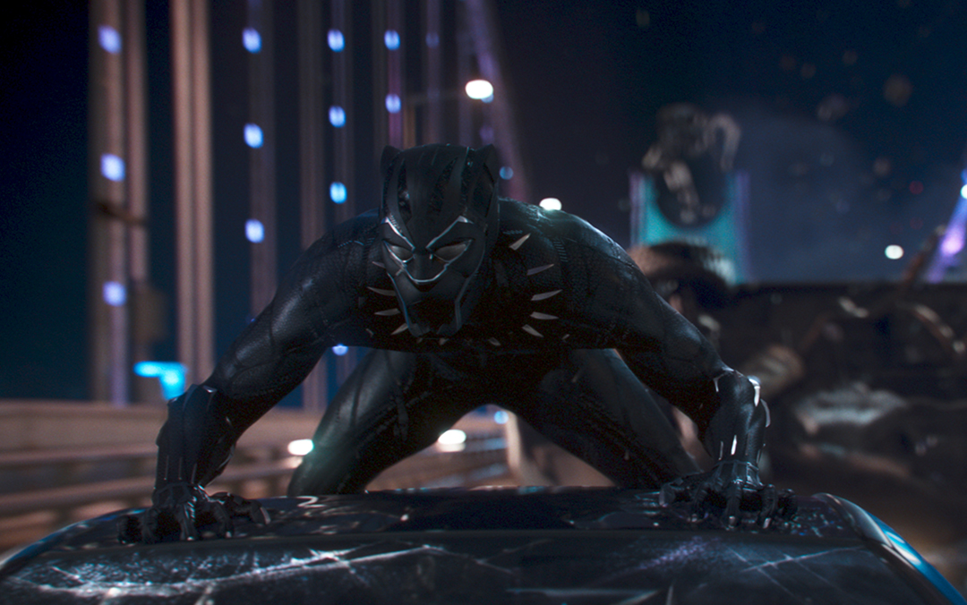 A scene from Marvel Studio's film Black Panther, where the title character crouches on top of a moving car on a bridge.