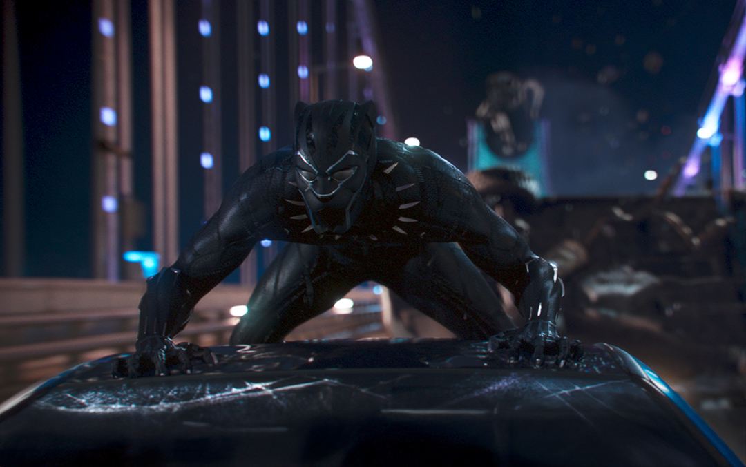 A scene from Marvel Studio's film Black Panther, where the title character crouches on top of a moving car on a bridge.