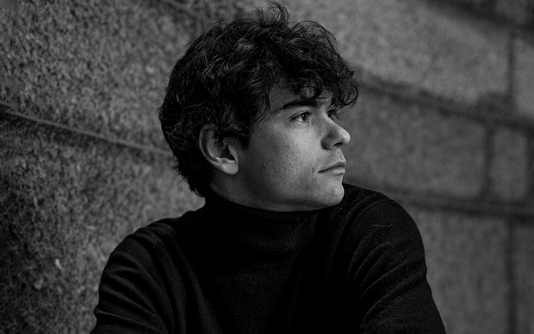 Pianist Tom Borrow, a white man in a black turtleneck, looks to the side in this black and white photo.