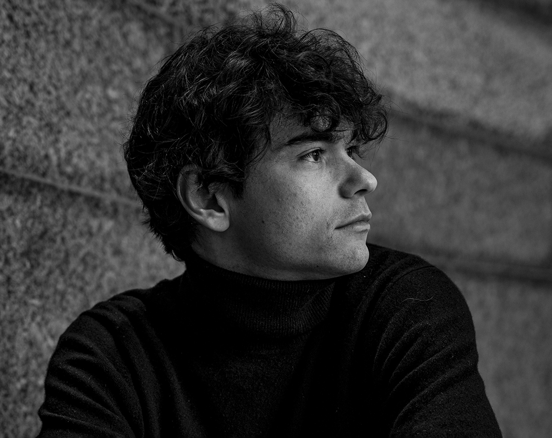 Pianist Tom Borrow, a white man in a black turtleneck, looks to the side in this black and white photo.