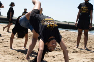 Aileycampers do acrobatic poses on a beach.