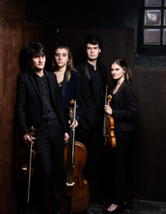 The four members of the Le Consort Courtesy group wear black formal dress, and pose together with their instruments in hand.