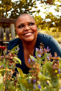 Tanya Holland smiling in a garden of flowers.