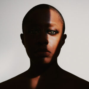 Cecile McLorin Salvant is covered by shadow except for a strip of light illuminating one of her green eyes.