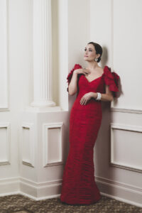Artist Erin Morley wearing a red dress looking off camera.
