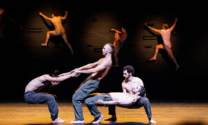 Dancers in the Batsheva Dance Group gather on-stage in an acrobatic stunt for their performance of MOMO.