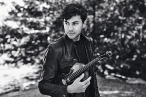 Black and white photo of Benjamin Beilman holding his violin.