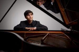 Evren Ozel sitting at a grand piano.