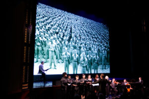 A choir sings in front of a projection of Story Boldly's Defining Courage.