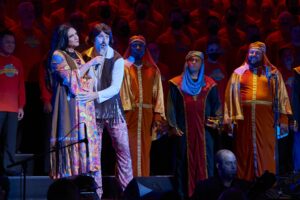 Singers of the San Fansisco Gay Men's Chorus are dressed in long orange costumes.