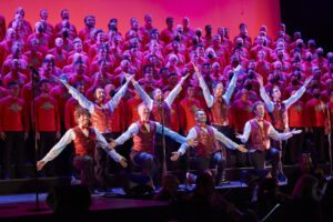 The San Francisco Gay Men's Chorus wear matching red vests and strike a final pose in their performance,