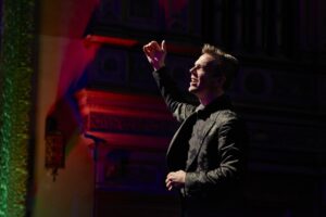 A man sings solo wearing a black suit.