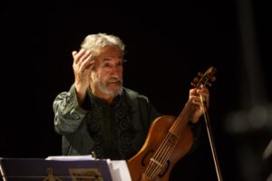 Jordi Savall gestures enthusiastically with one hand as he holds his viol in his other hand.