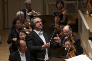 Riccardo Muti conducts the Chicago Symphony Orchestra with a serious expression on his face.