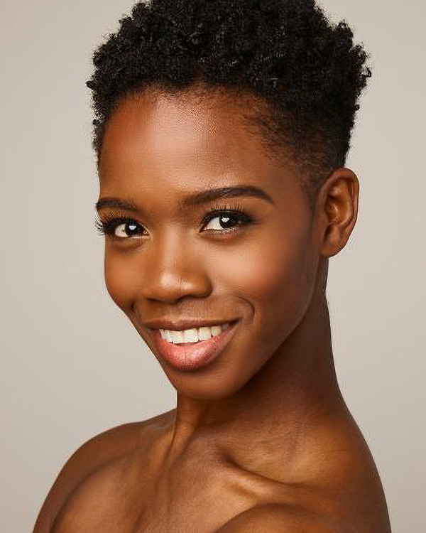 A portrait photo of Jessica Amber Pinkett, a young black woman with rosy cheeks and short curly hair from the Alvin Ailey American Dance Theater.
