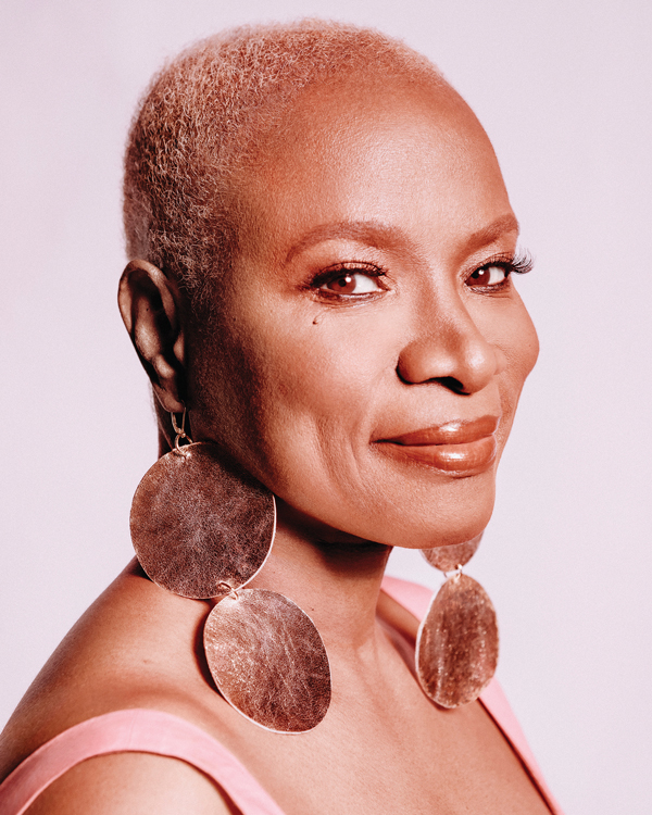 A close up portrait of artist Angelique Kidjo, a Beninese-French woman with buzzed hair and large statement earrings.
