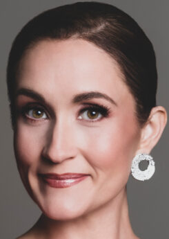 Portrait photo of artist Erin Morley, with brown hair pulled back into a bun and large silver circle-shaped earrings.
