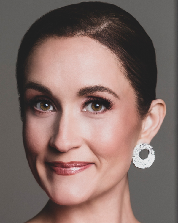 Portrait photo of artist Erin Morley, with brown hair pulled back into a bun and large silver circle-shaped earrings.