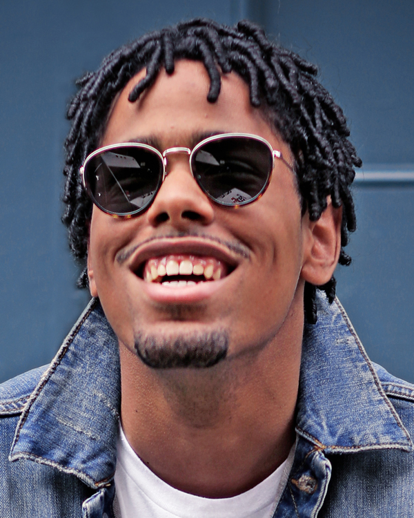 Artist Matthew Whitaker wearing sunglasses and a jean jacket, smiling joyously.