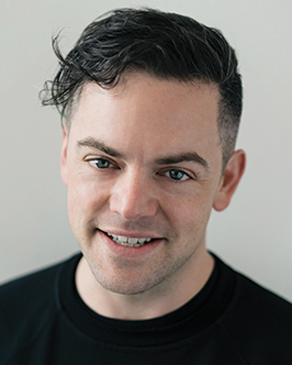 Portrait image of artist Nico Muhly, looking slightly off camera with bright blue eyes.