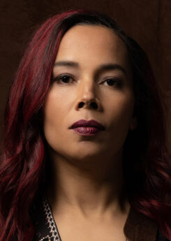 Artist Rhiannon Giddens wears dark burgundy lipstick that matches her hair color in this portrait photo.