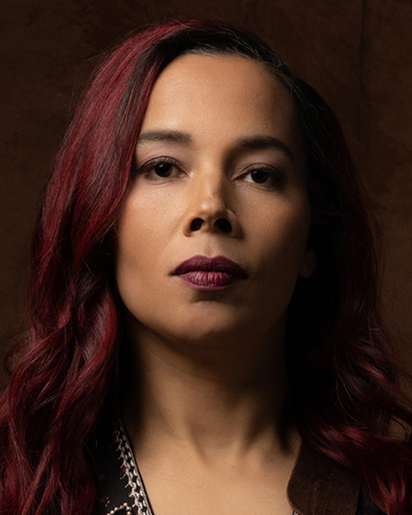 Artist Rhiannon Giddens wears dark burgundy lipstick that matches her hair color in this portrait photo.