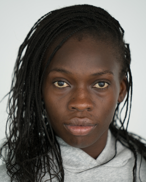 A portrait photo of artist Rokhaya Coulibaly, wearing her hair in tiny braids and a side part.