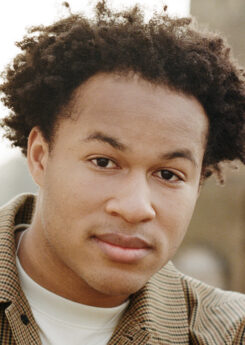 Photo of artist Sheku Kanneh Mason wearing a plaid overshirt.