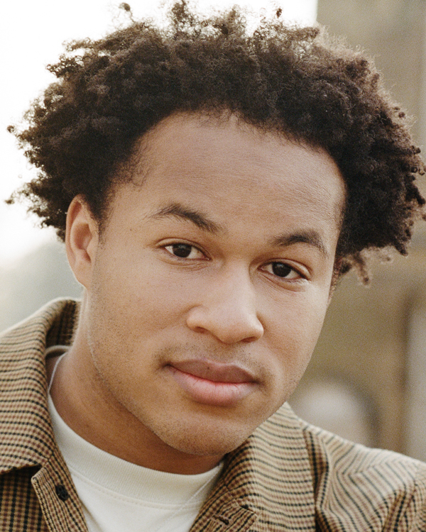 Photo of artist Sheku Kanneh Mason wearing a plaid overshirt.