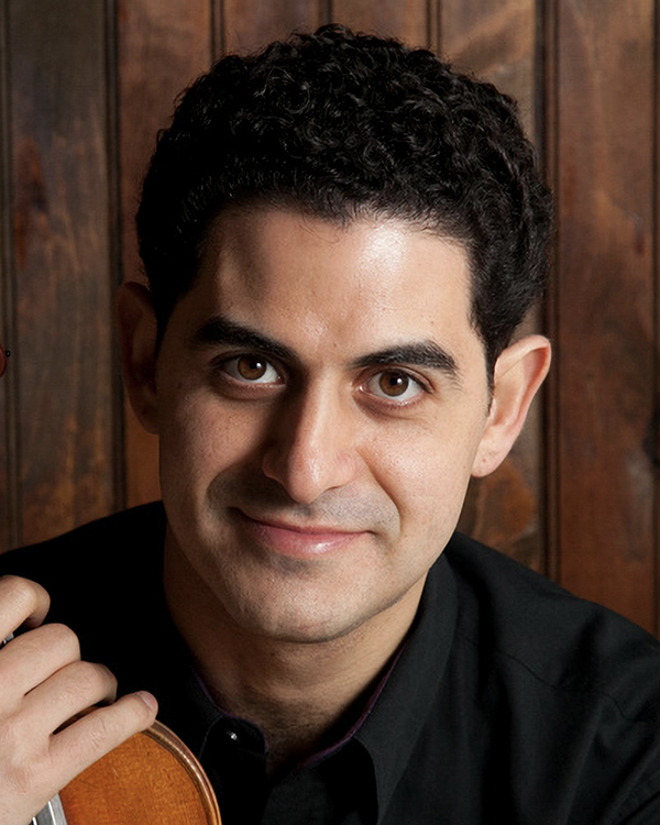 A headshot image of Arnaud Sussmann, a man with dark, curly hair in a black shirt, looking into the camera.