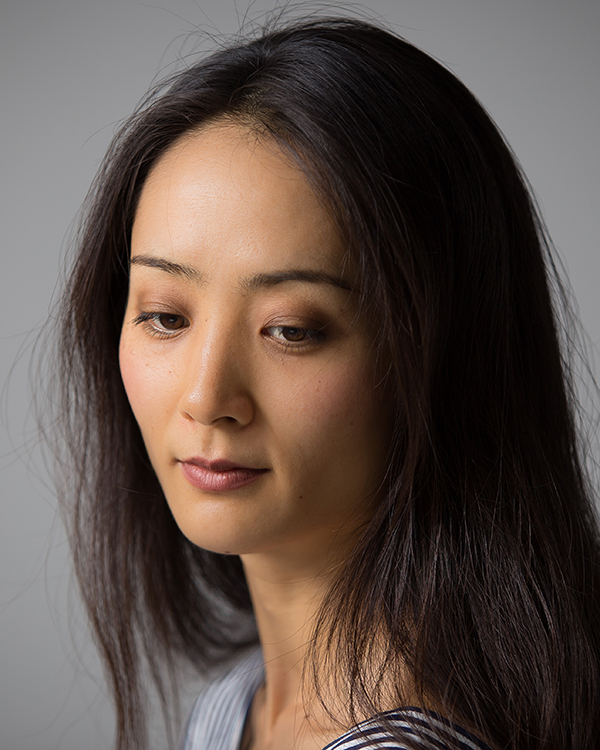 Eri Nakamura, an Asian woman with long dark hair, looks down at something below the camera