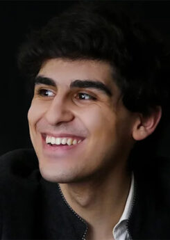 Evren Ozel, a young man with dark hair, smiles largely to his left