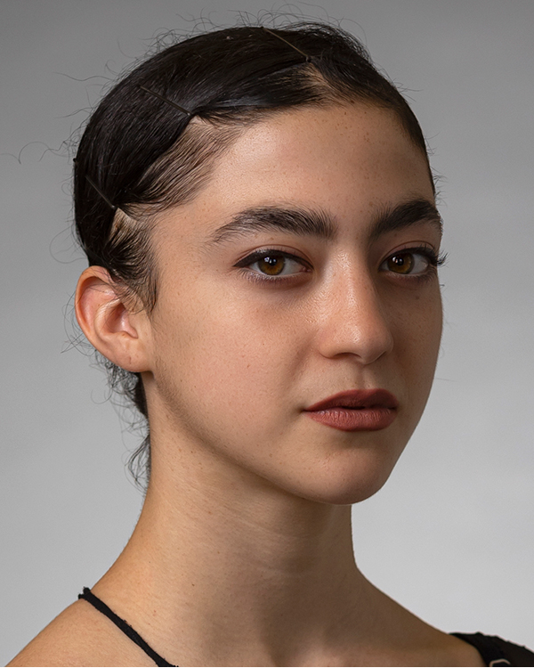 Gili Yaniv Amodai, a lightskinned woman with her dark hair slicked back, looks into the camera