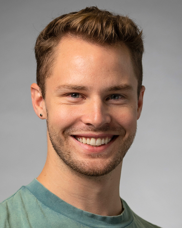 Sean Howe, a light-skinned man with short light brown hair, smiles widely into the camera