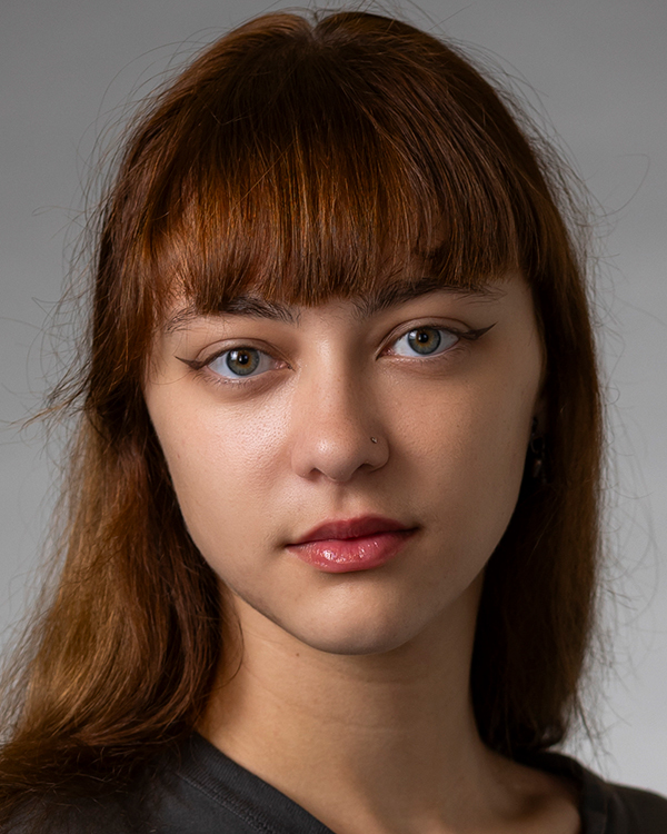 Sofiia Pikalova, a light-skinned woman with long red hair and bangs, looks softly into the camera