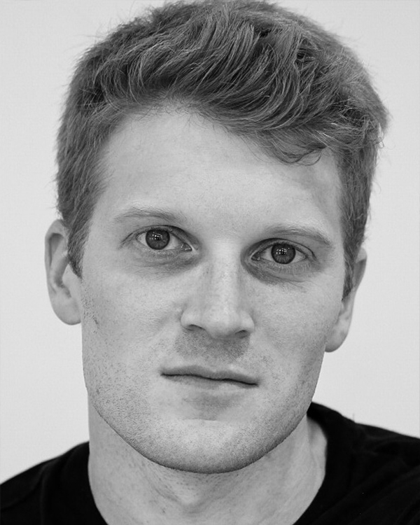 A black-and-white headshot image of Alexander Peters, a white man with short hair, looking into the camera.