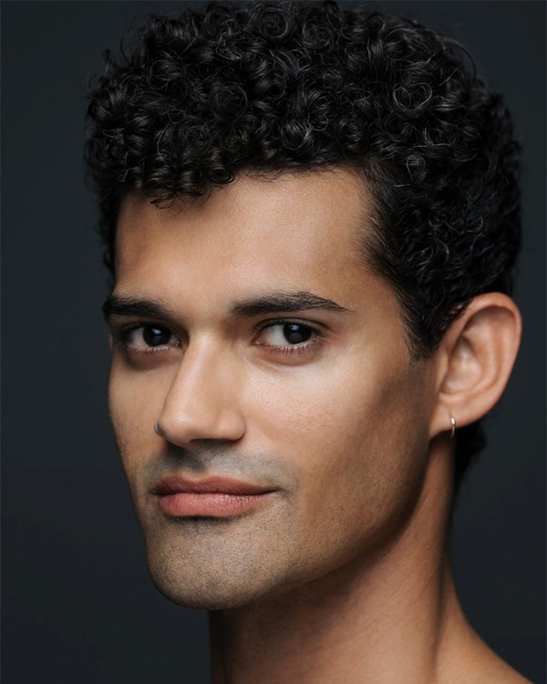 A headshot image of Renan Cerdeiro, a medium-olive skinned man with curly dark hair looking into the camera