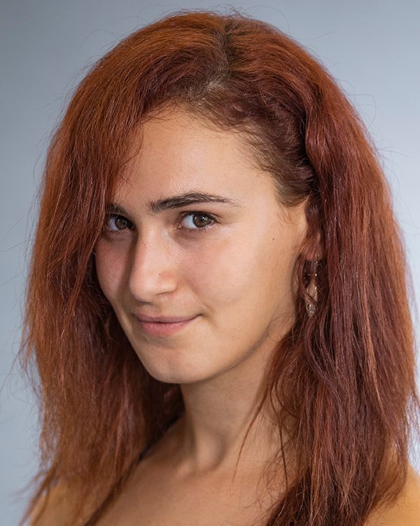 Yarden Bareket, a light olive-skinned woman with long red-orange hair, smiles into the camera