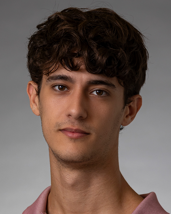 Yarden Zana, an olive-skinned man with curly brown hair, stares into the camera