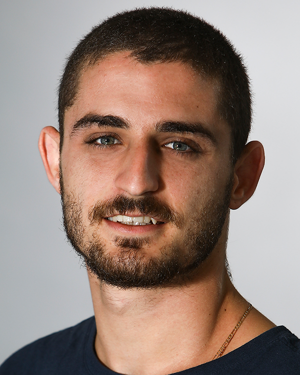 Yoni (Yonatan) Simon, a light-skinned man with a dark buzzcut and beard, smiles slightly into the camera