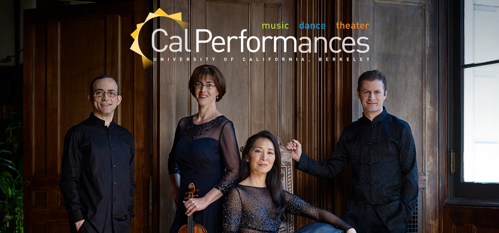 The Brentano String quartet, two men and two women in formal attire, pose with the two women in the center, one seated, and the men standing at the ends