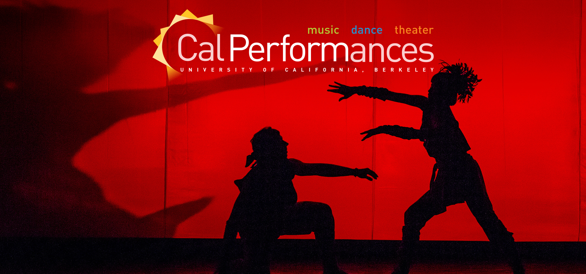 The silhouettes of two dancers of the Twyla Tharp Dance Troupe onstage in front of a red background, one on one knee and the other reaching out to the former.